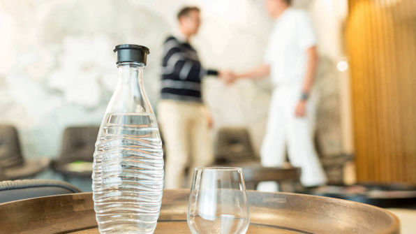 Wasserflasche mit Glas auf Tablett